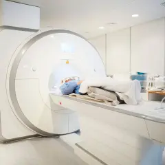 Pacjent leży w aparacie rezonansu magnetycznego, przygotowując się do badania mr kręgosłupa.