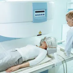 Pacjentka leży w aparacie MRI, a technik przygotowuje badanie. Czy rezonans głowy obejmuje szyję? To zależy od protokołu badania.