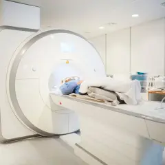 Pacjent leży w aparacie do rezonansu magnetycznego. Badanie to jest kluczowe, by dowiedzieć się, ile trwa rezonans kręgosłupa.