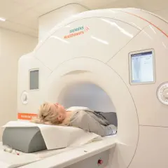 Kobieta leży w aparacie do rezonansu magnetycznego, przygotowując się do badania miednicy.