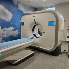 Nowoczesny tomograf komputerowy Philips w gabinecie z chmurami na ścianie. Częstotliwość badań zależy od wskazań lekarza.