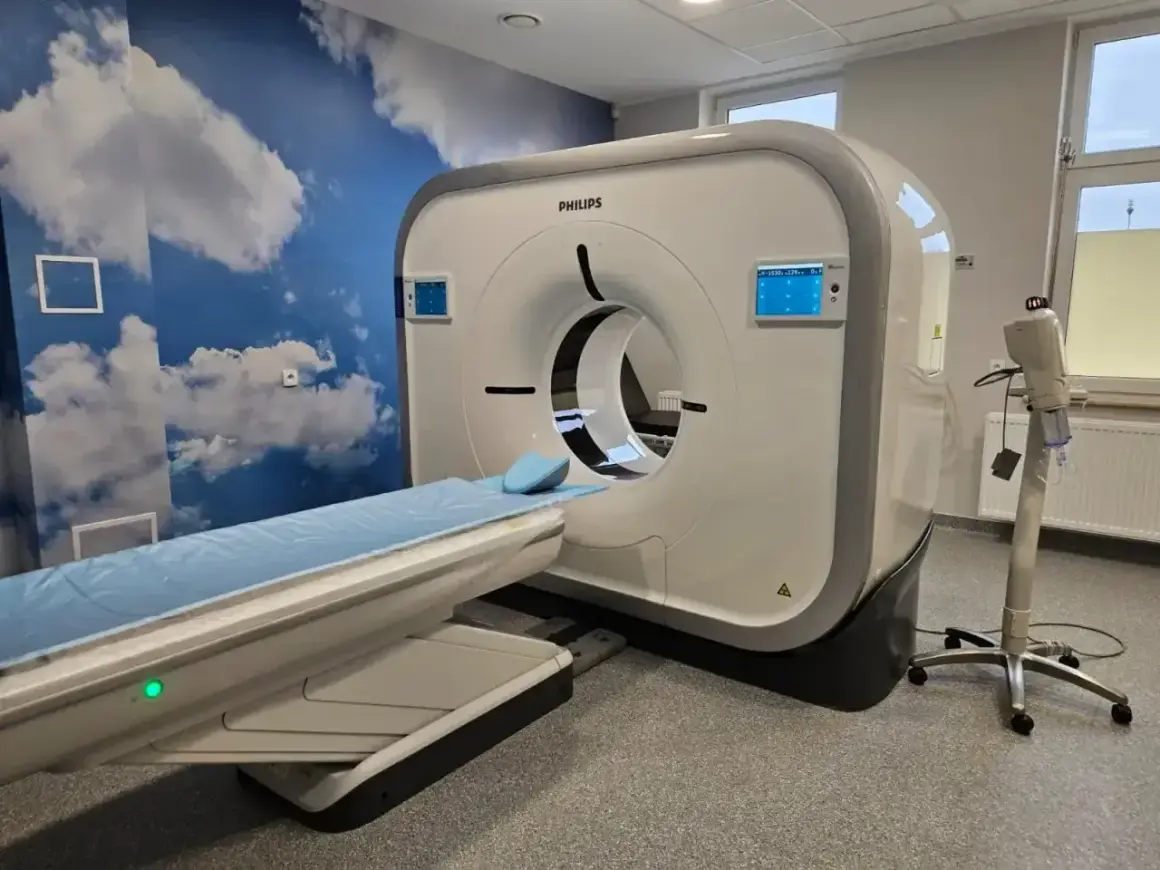 Nowoczesny tomograf komputerowy Philips w gabinecie z chmurami na ścianie. Częstotliwość badań zależy od wskazań lekarza.